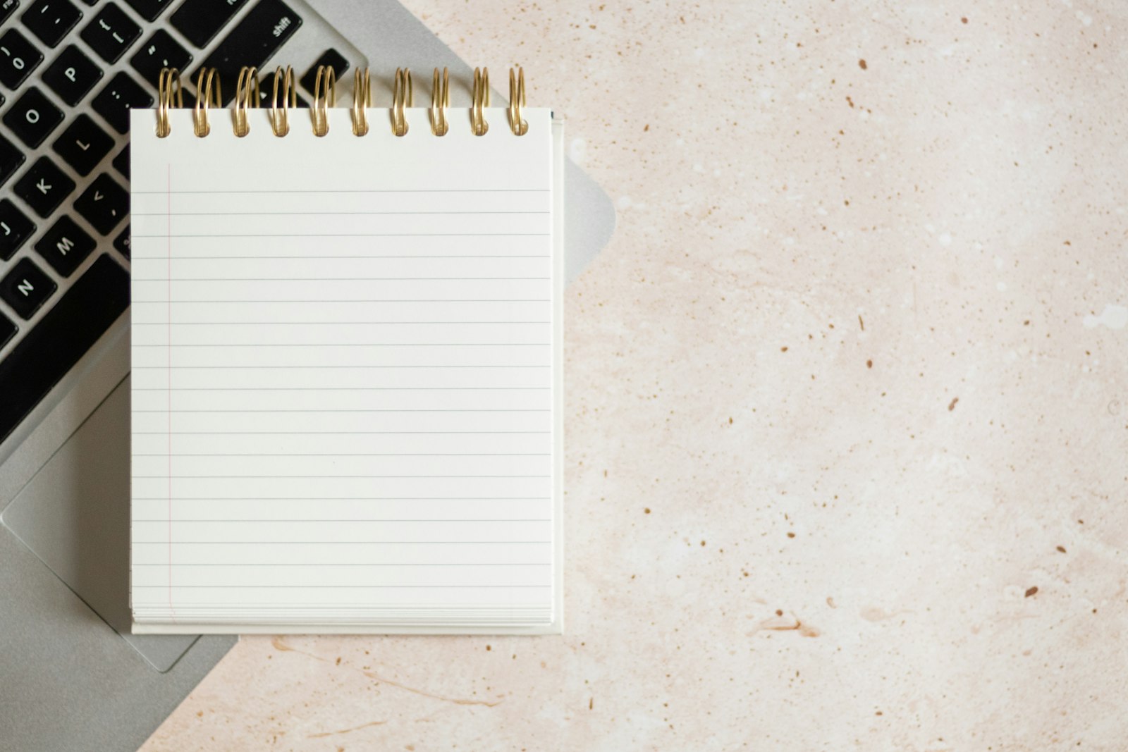 Notebook resting on a laptop, representing drafting requirements before coding.